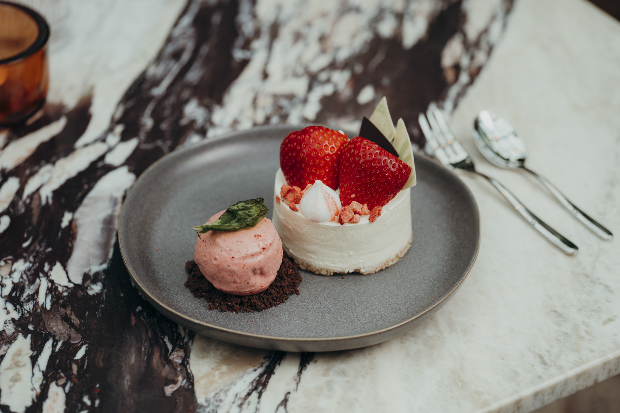 Ein Dessertteller mit einem kleinen Käsekuchen mit Erdbeeren und einer ...