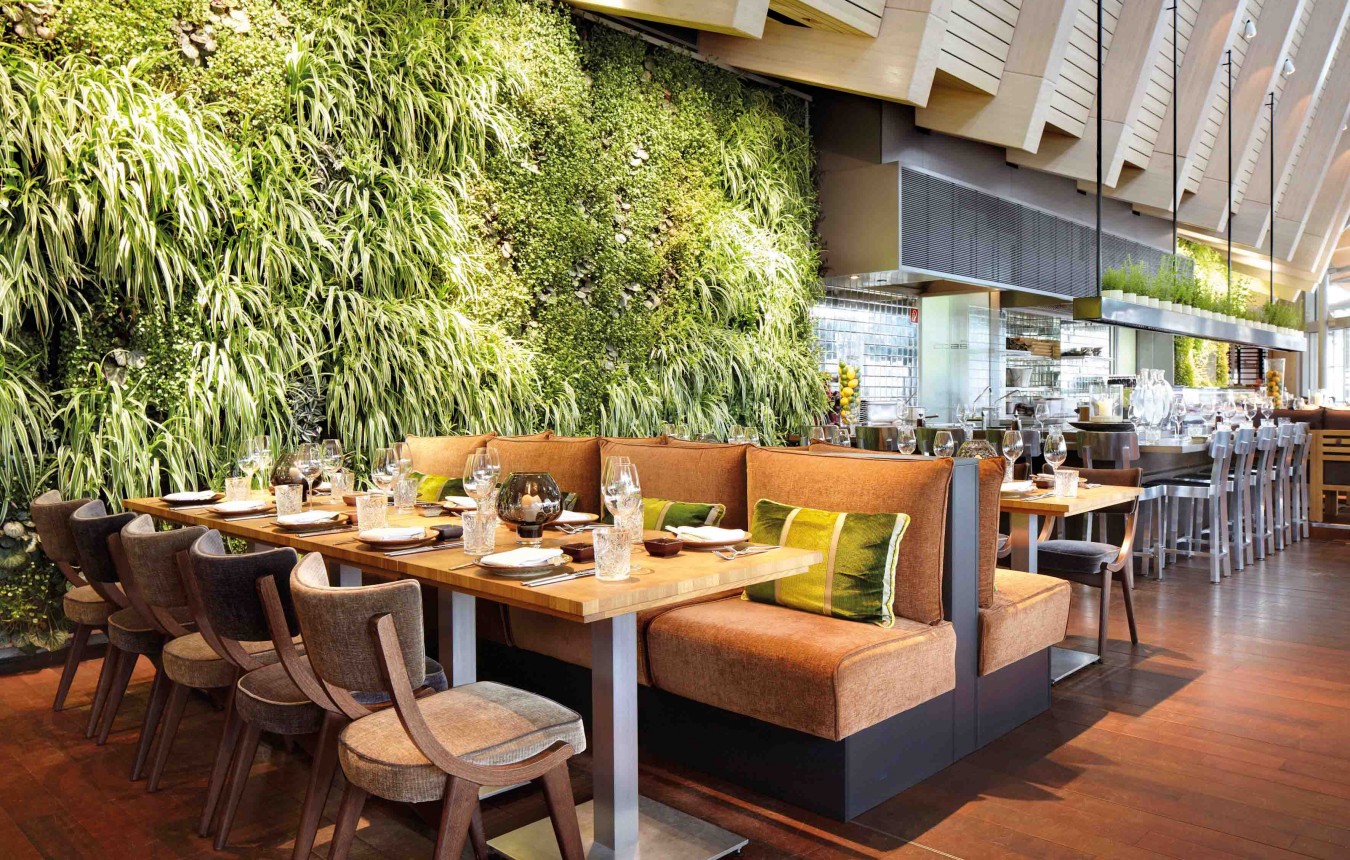 Sitzgruppe im coast by east Restaurant mit bepflanzter Wand und Sushibar