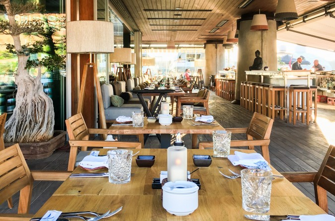 Außenbereich des coast Mallorca Restaurants mit langer Tafel, Bar und Bonsaibaum