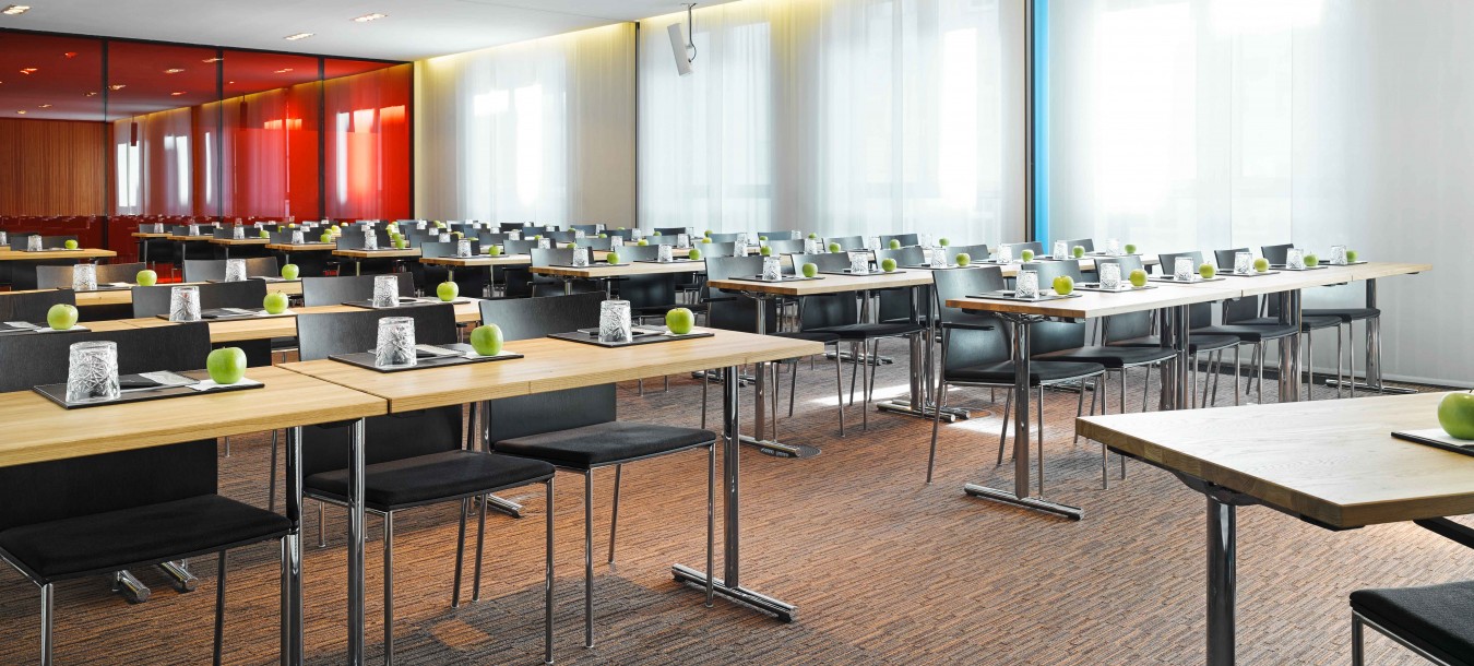 Conference room with rows of tables and green apple on each seat