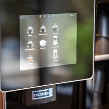 Eine Nahaufnahme des Touchscreens einer Kaffeemaschine, auf dem verschiedene Kaffeegetränkeoptionen angezeigt werden.