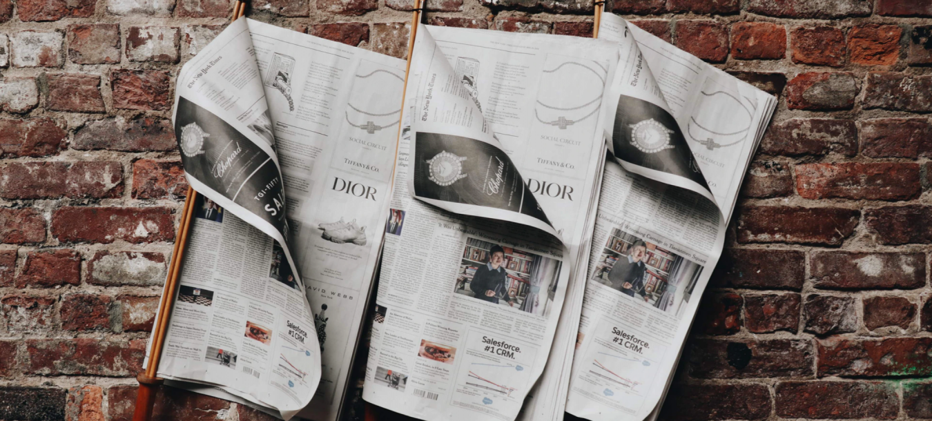 Newspapers hang on a brick wall