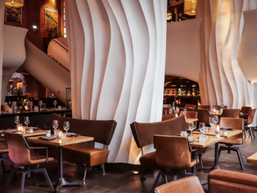 Restaurant seats with tables, brown chairs and benches in front of a rotated column